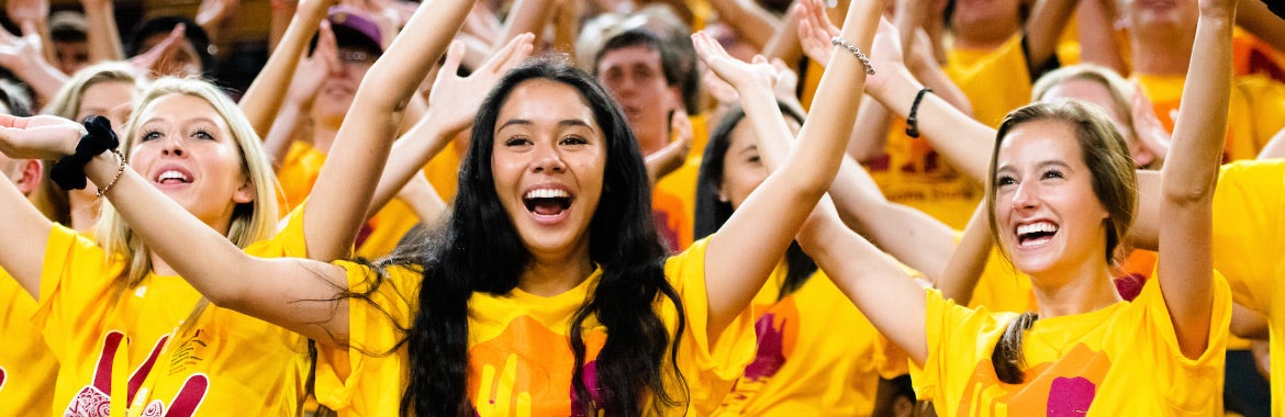 college students wearing gold ASU shirts, cheering, and raising their arms